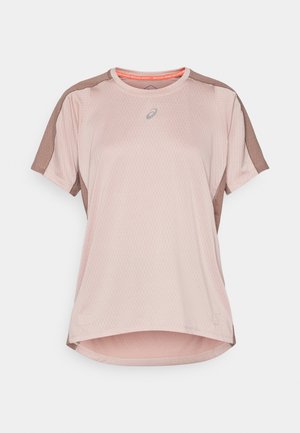 Camiseta deportiva de color rosa claro con un cuerpo de malla texturizada, mangas marrones y un dobladillo redondeado. Presenta un logo en el cuello delantero y detalles en color naranja.