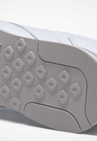 Weißer Sneaker-Sohlen mit einer strukturierten grauen Gummibasis, die ein Muster aus erhöhten Quadraten und vertikalen Rillen zeigt. Glatte obere Fläche.