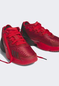 Las zapatillas deportivas rojas cuentan con una parte superior texturizada con un patrón de espiga, acentos negros y cordones redondos. Su suela gruesa ofrece amortiguación.