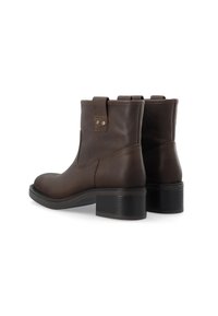 Botas de tobillo de cuero marrón con puntera redondeada, tacón y dos botones decorativos cerca de las lengüetas. Suelas exteriores resistentes y texturizadas que mejoran el agarre.