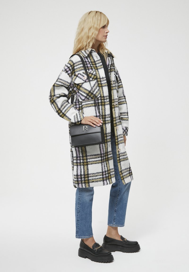 Płaszcz w kratę w kolorze białym, żółtym i czarnym, zestawiony z ciemnymi dżinsami i czarnymi loafersami na platformie. Posiada klapowe kieszenie i luźny krój.