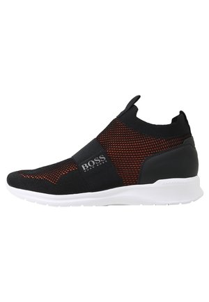 Sort og rød strikket slip-on sneaker med elastikbånd mærket "BOSS Hugo Boss" og hvid sål, set fra siden.