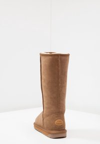 Bota de ante beige hasta la rodilla con un suave forro interior, suela de goma plana y detalles de costura. Logo de EMU Australia en el talón.