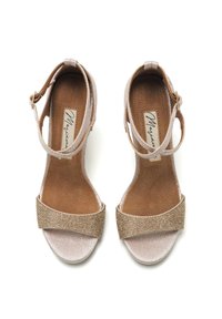 Sandales beiges à lanières avec une bande dorée texturée à l'avant, semelle en daim et brides de cheville avec des boucles en métal.