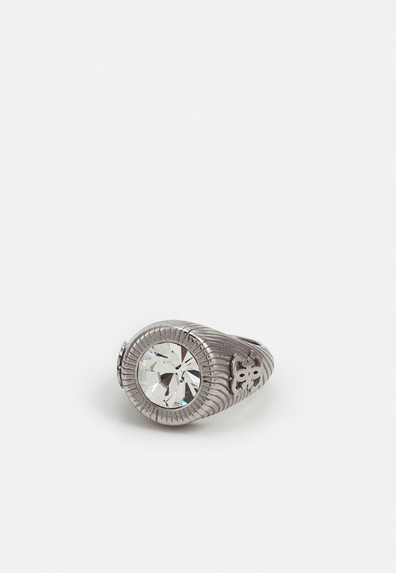 Bague en argent avec une grande pierre précieuse ronde claire et des motifs décoratifs gravés sur l'anneau, sur un fond blanc uni.