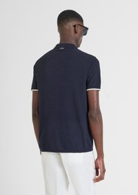 Polo a maniche corte blu navy, tessuto texturizzato, bordi con trim bianco, colletto con un piccolo etichetta sul retro, vestibilità casual.