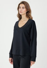 Czarna bluza z dekoltem w serek, długimi rękawami, prążkowanym wykończeniem, w luźnym kroju, wykonana z miękkiego, lekkiego materiału.