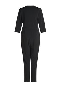 Tutina nera realizzata in tessuto elasticizzato, con maniche a tre quarti, vita aderente e gambe svasate. Nessun motivo o accessorio in vista.