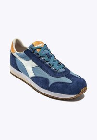 Sneaker blu navy realizzato in materiali scamosciati e in tela, con logo bianco, lacci turchesi e suola in gomma marrone.