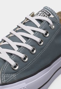 Μπλε καμβάς αθλητικό παπούτσι με λευκά κορδόνια, μεταλλικά ρουλεμάν, ορατή ραφή και λευκή λαστιχένια σόλα με μαύρη ρίγα.