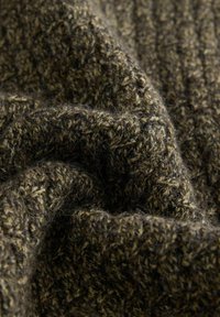 Detailný záber tmavozelenej pletenej vlnenej tkaniny s textúrovanými káblovými vzormi a viditeľnými jemnými vláknami.