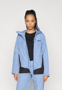 Ανοιχτό μπλε αδιάβροχο μπουφάν με κουκούλα, μαύρες λεπτομέρειες, μπροστινούς φερμουάρ και πλαϊνές τσέπες. Διαθέτει άνετη εφαρμογή και λεία υφή.