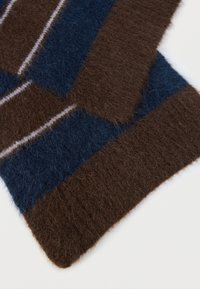Brown, blue, and cream striped scarf made of fuzzy knitted material; features a ribbed edge and soft texture.
