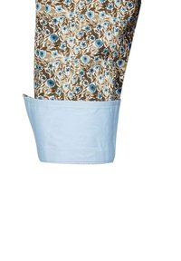 Tessuto a fantasia floreale con fiori blu su sfondo marrone; polsino in cotone azzurro chiaro con texture liscia e orlo cucito.