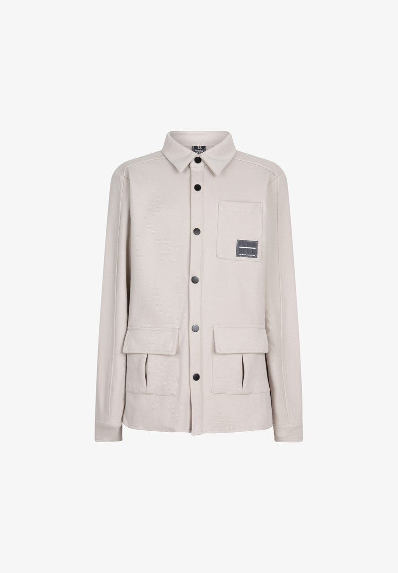 Helle beige Jacke mit langen Ärmeln, Knopfriegel, spitzem Kragen, zwei Vordertaschen und einer Brusttasche mit einem Logopatch.