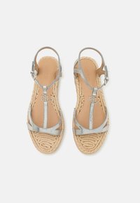 Silverfärgade metalliska remsandaler med vävda jutesulor och spännen runt anklarna, med "RL"-logotcharm på de främre remmarna.