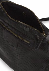 Bolso de mano de cuero negro con una superficie texturizada, apertura con cremallera y un bolsillo exterior. Presenta herrajes y costuras en tono dorado.
