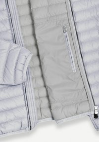 Svetlo siva prešita jakna, odprta, prikazuje notranji žep z vertikalno zadrgo in črnimi zobmi zadrge ob sprednjem robu.