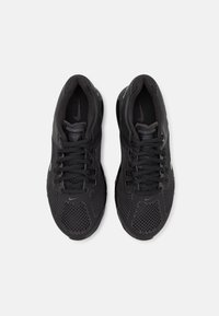 Svarta sportskor med övre i andningsbart mesh, texturerade detaljer, platta snören och en dämpad sula. Har en framträdande Nike-logotyp.