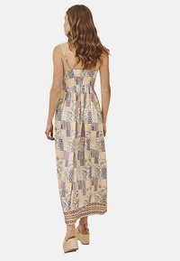 Vestido maxi con tirantes finos, tejido estampado en amarillo y azul, presenta un corsé ajustado y una falda fluida, complementado por un dobladillo detallado.