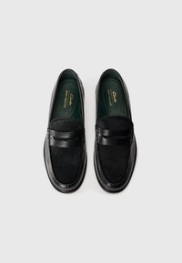 Mocasini negri, cu un pată din piele netedă și un panou texturat, formă rotundă, cusături discrete și insole moi.