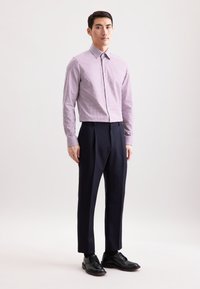 Lichtpaarse en witte gingham-patroon overhemd met knopen, gecombineerd met donkerblauwe op maat gemaakte broek en zwarte schoenen, staand op een lichte achtergrond.