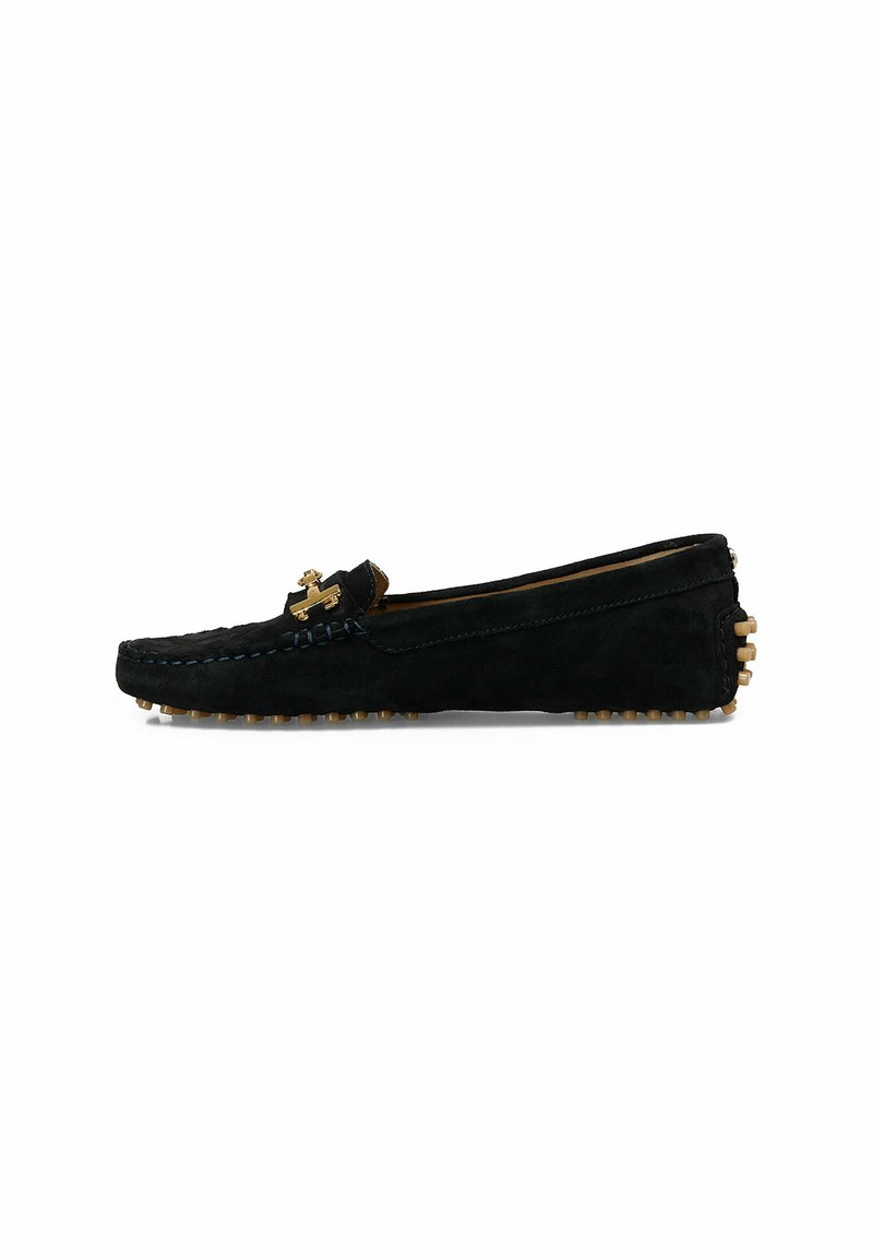 Sorte ruskind slip-on sko med et quiltet design, guldfarvede hardware detaljer og en gummisål med runde nitter for bedre greb.