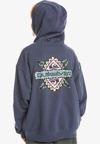 Námořnická modrá mikina s kapucí, která na zadní straně obsahuje velký barevný grafický design s abstraktními tvary a textem, vyrobená z měkkého materiálu s obsahem bavlny.