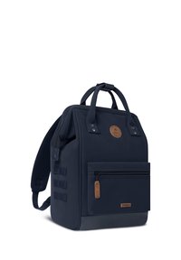 Zaino blu navy con un design strutturato, con patch in pelle, tasca frontale con zip, maniglie superiori e spallacci imbottiti.