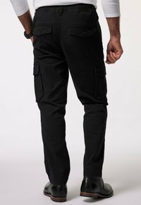 Zwarte cargobroek met een slim fit, voorzien van zijzakken, een elastische tailleband en een gladde textuur. Draagt met zwarte leren schoenen.