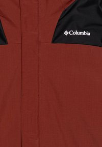 Columbia-jakke med et teksturert rustrødt stoff og svarte detaljer. Inkluderer en logo på øvre venstre side og et elegant glidelåssystem.