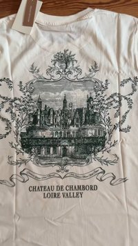 Biała koszula z szczegółowym czarnym szkicem Château de Chambord otoczonym ozdobnymi wzorami kwiatowymi, opisaną jako "Loire Valley."