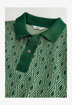 Green polo shirt featuring a geometric diamond pattern, knit collar, and two buttons. The fabric exhibits textured and smooth contrasts.