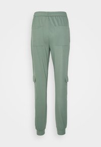 Calças de jogging verdes feitas de um tecido macio, com um cós elástico, dois grandes bolsos na parte de trás e punhos estreitados ao nível do tornozelo.