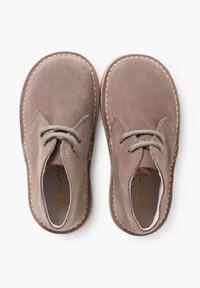 Scarpe in suede marrone con punta arrotondata, lacci grigi e dettagli di cucitura a contrasto attorno alla suola. Design minimalista con una forma comoda.
