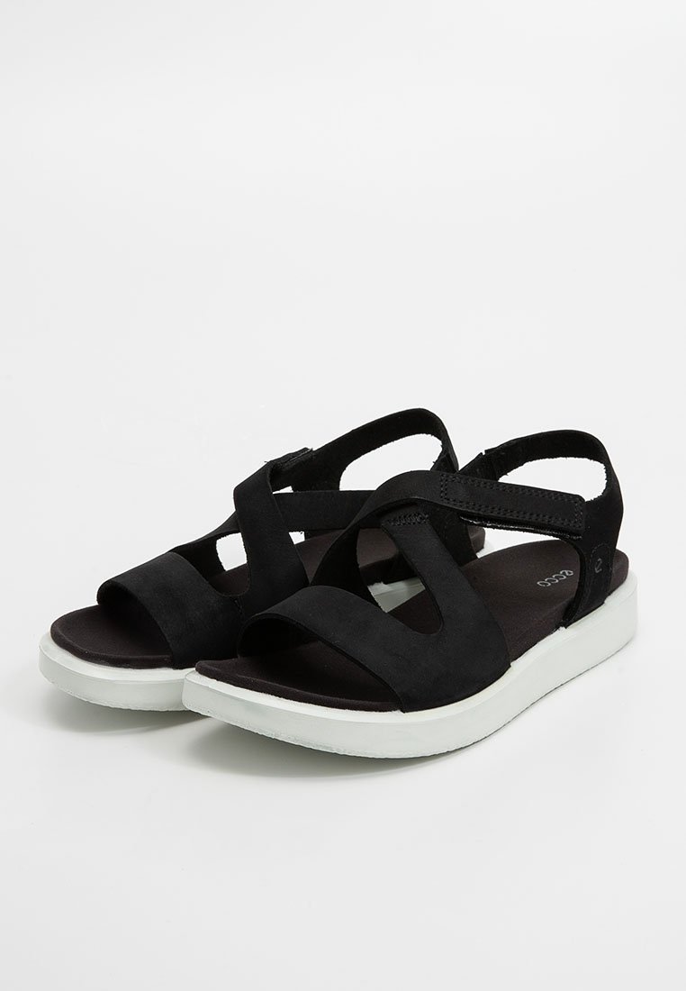 Zwarte sandalen met brede kruislings banden, open neuzen, gevoerde voetbedden en dikke witte zolen op een witte achtergrond.