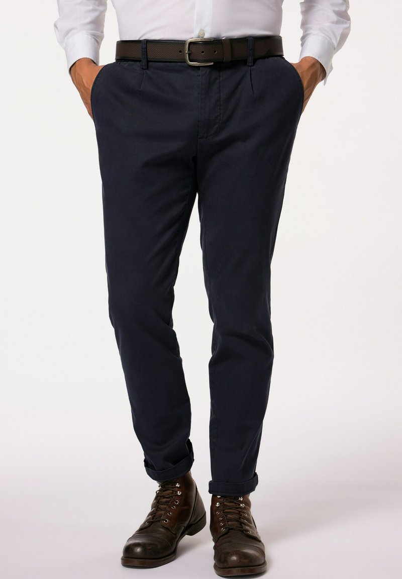 Chinos blu navy in cotone con una trama liscia, design affusolato e due tasche laterali, abbinati a stivali in pelle marrone e una cintura.