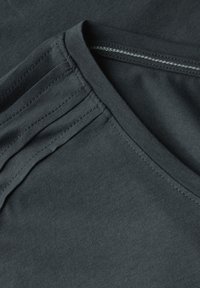 Camiseta de algodón gris oscuro con diseño de cuello en V, que presenta una textura suave y sutiles detalles de costura cerca de los hombros.