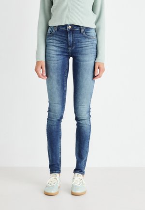 Slanke jeans i medium blå denim med høj talje, to frontlommer og en subtil falmeffekt. Bæres med lyseblå sneakers.