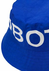 Niebieski kapelusz typu bucket wykonany z gładkiego materiału, z szerokim rondem i wyraźnym białym napisem z boku. Widoczne przeszycia wzdłuż krawędzi.