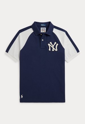 Marineblå og hvid kortærmet poloshirt med New York Yankees-logo på brystet og lille hvid Ralph Lauren-emblem nær kanten.