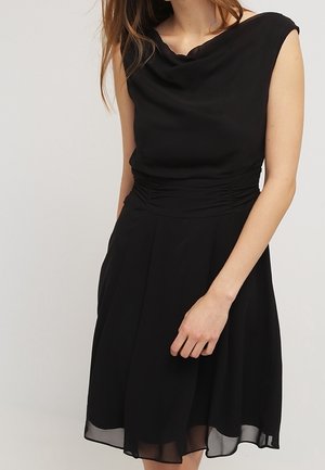 Schwarzes ärmelloses Kleid mit Wasserfallausschnitt, geraffter Taille und fließendem Rock. Merkmale sind ein transparenter Saum und eine glatte Stoffstruktur.