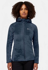 Giacca in pile blu scuro con zip frontale e cappuccio. Caratteristiche includono tessuto testurizzato, tasche laterali e logo sul petto.