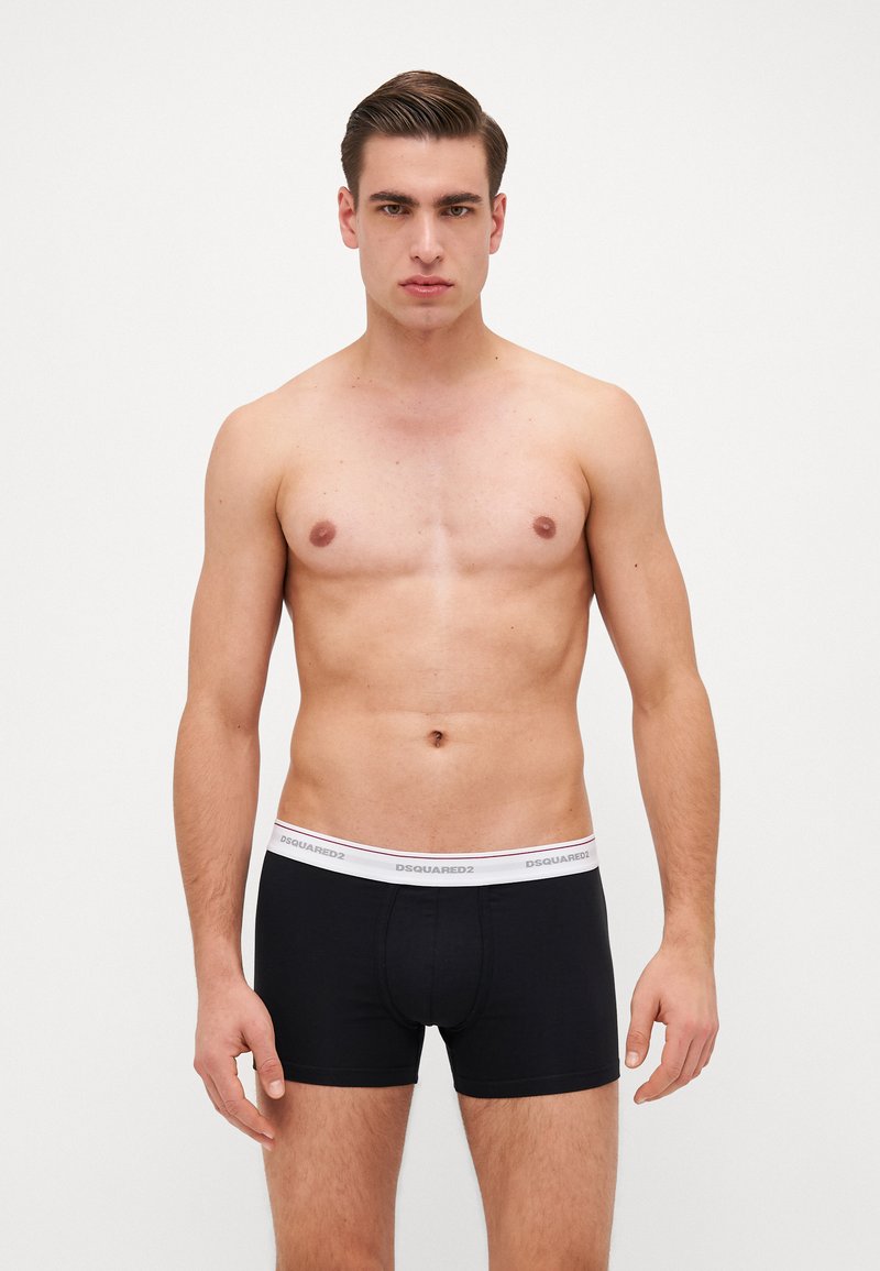 Schwarze Boxershorts mit einem weißen elastischen Bund, der den Markennamen "DSQUARED2" trägt. Der Stoff wirkt glatt und eng anliegend.