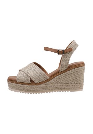 Sandalia de cuña beige con correas de tejido trenzado, correa en el tobillo ajustable y suela de yute texturizada. Plantilla de cuero marrón suave.
