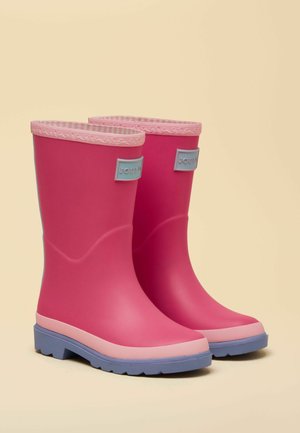  Paar keskpikkuseid erkroosat kummisaapaid heledate roosade ääriste, siniste taldade ja sinise "Joules" logoga kahvatu taustal.