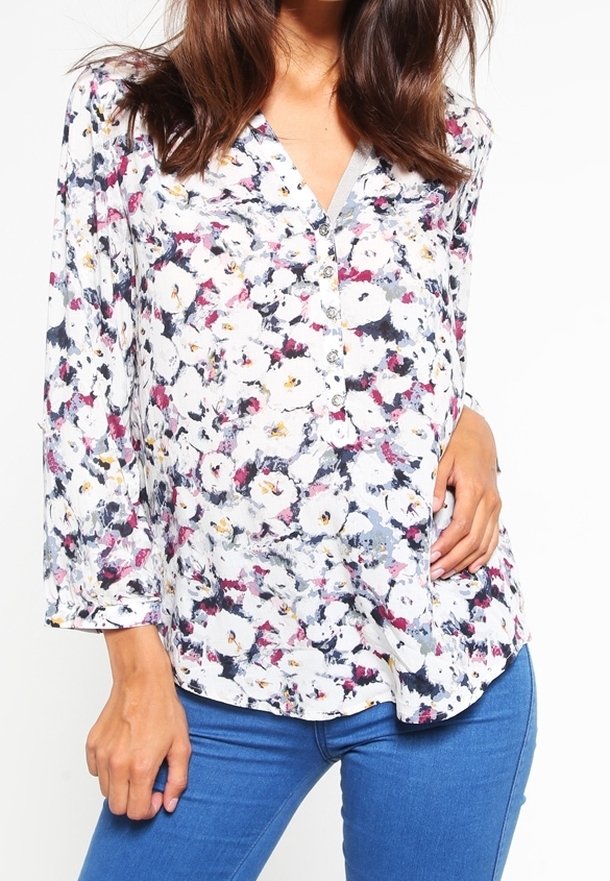 Blouse fleurie avec une base blanche, comportant un imprimé coloré de fleurs roses, jaunes et bleues, col en V, devant boutonné et manches longues.