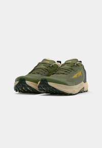 Trail running shoes with a green mesh upper, cream midsole, and black rubber outsole featuring aggressive tread for traction.