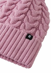 Różowa dziana czapka z kabelkowym wzorem i ściągaczem. Widoczna mała czarna metka z białą literą „R”.