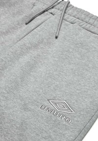 Pantalons de survêtement gris en matière douce avec une taille élastique, dotés d'un cordon de serrage et d'un logo "Umbro" brodé sur la jambe inférieure.